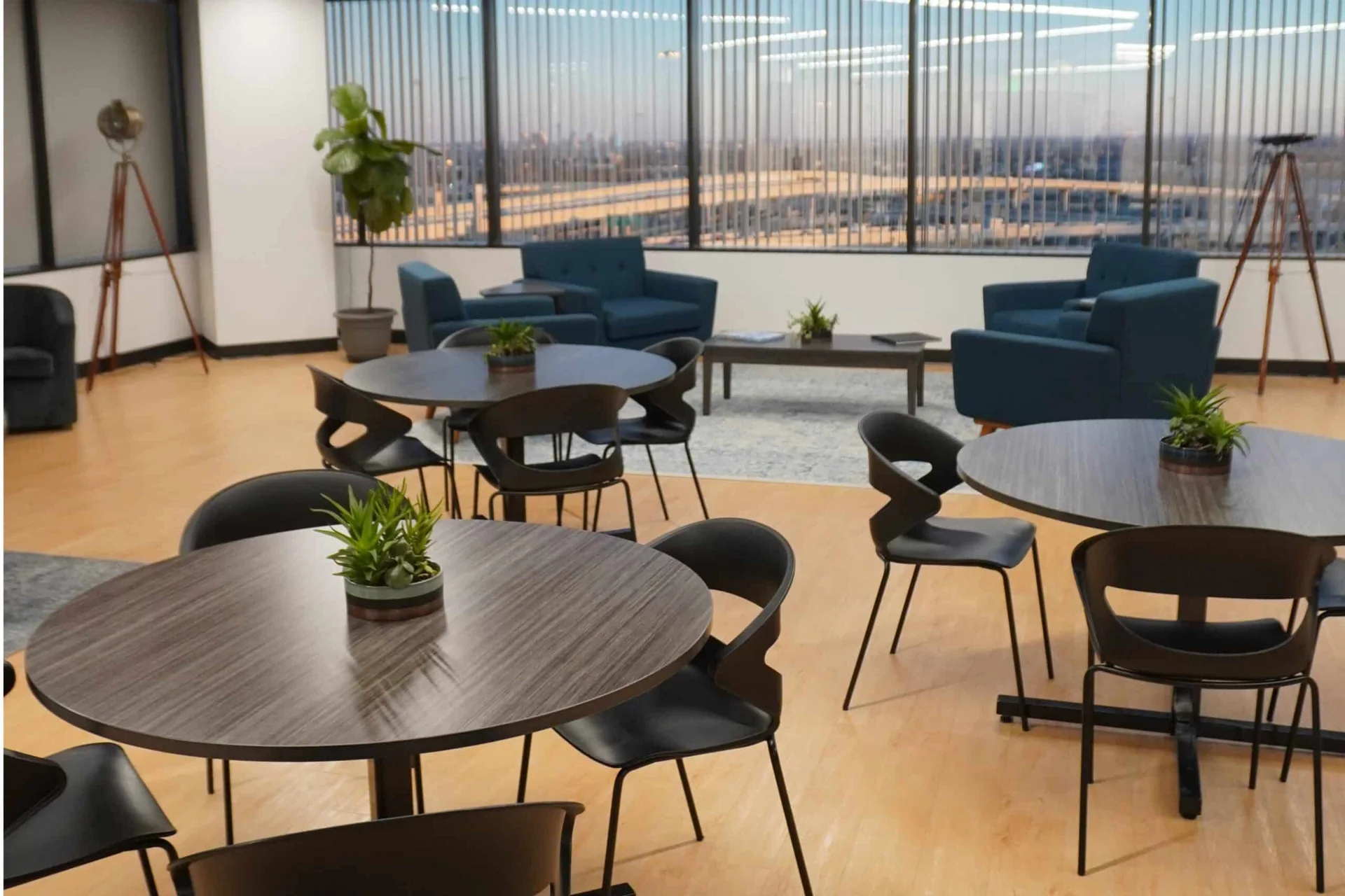 Shared tables and lounge seating at SA Cowork in Northwest San Antonio, with views over I-10