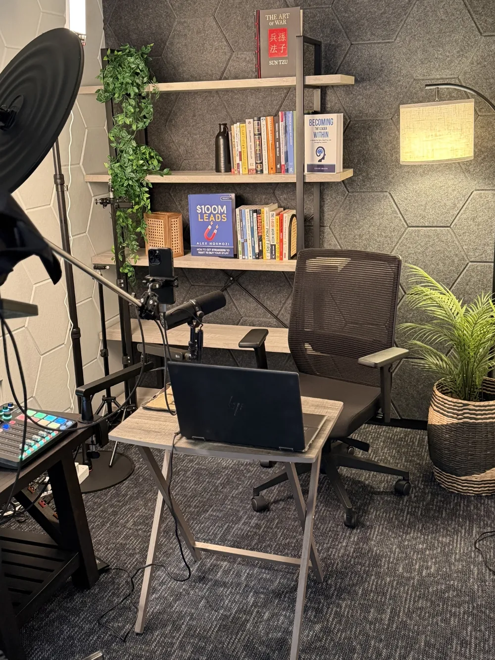 The one-person podcast studio at SA Cowork in San Antonio, with a broadcast microphone, teleprompter, ring light and acoustic hexagon panelling